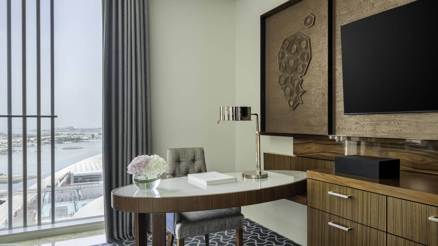 Hotel room with desk, dresser and wall-mounted TV