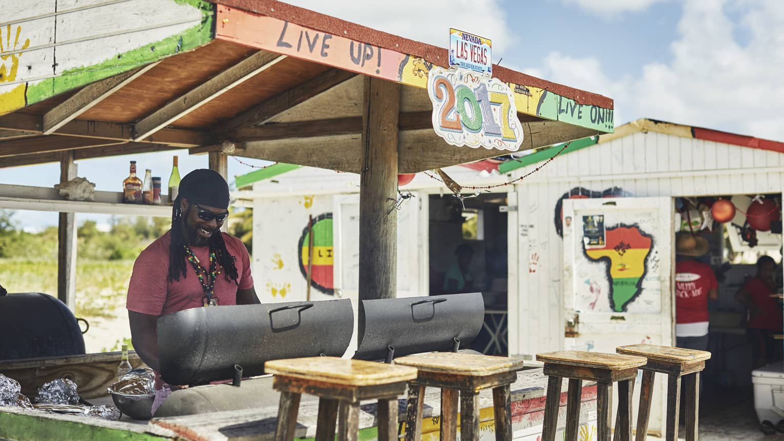 Smiling man grilling at colourful outdoor barbecue stand