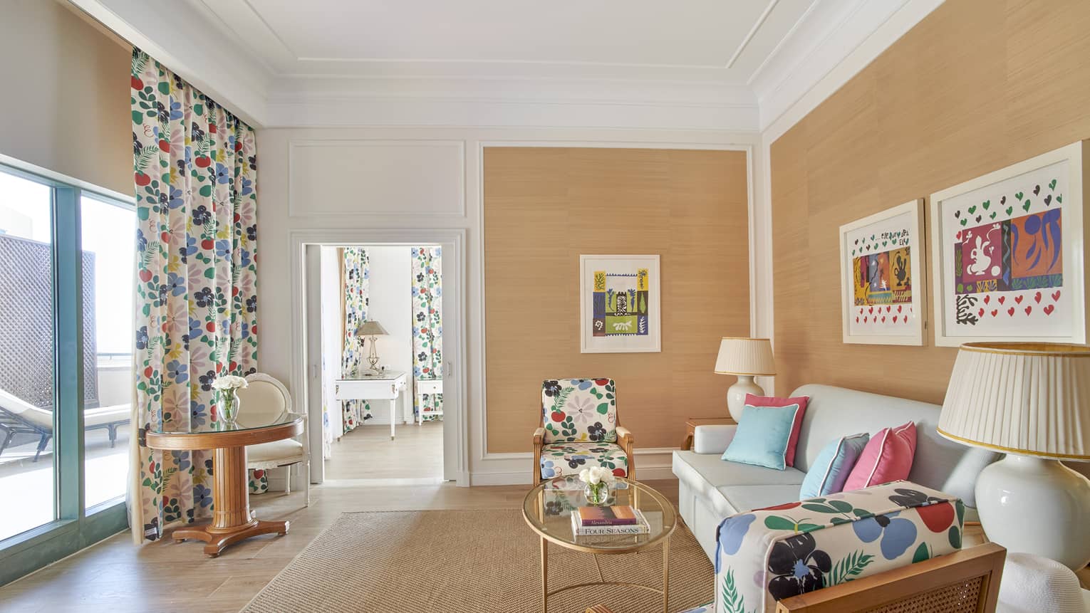 Living room with salmon-coloured walls, wood floors, printed curtains and arm chairs
