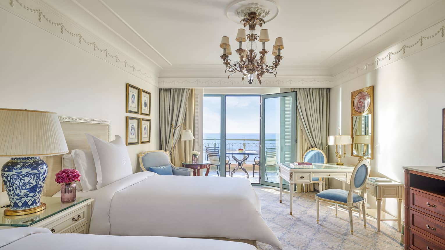 Sea View Room with twin beds, vanity table and two chairs, armchair, glass door to veranda