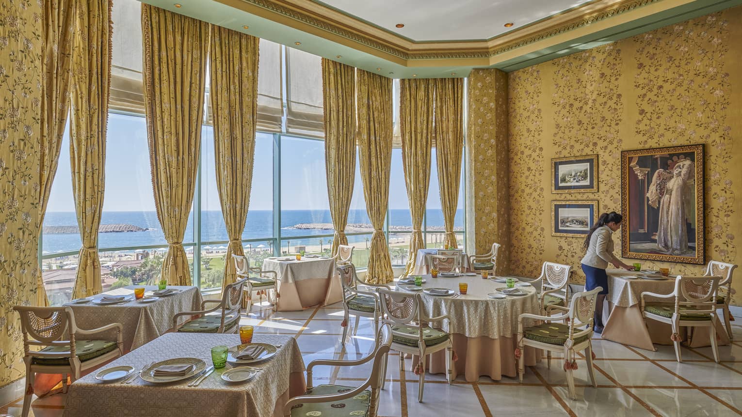 An empty Byblos restaurant is ready for guests with set tables and drawn yellow curtains