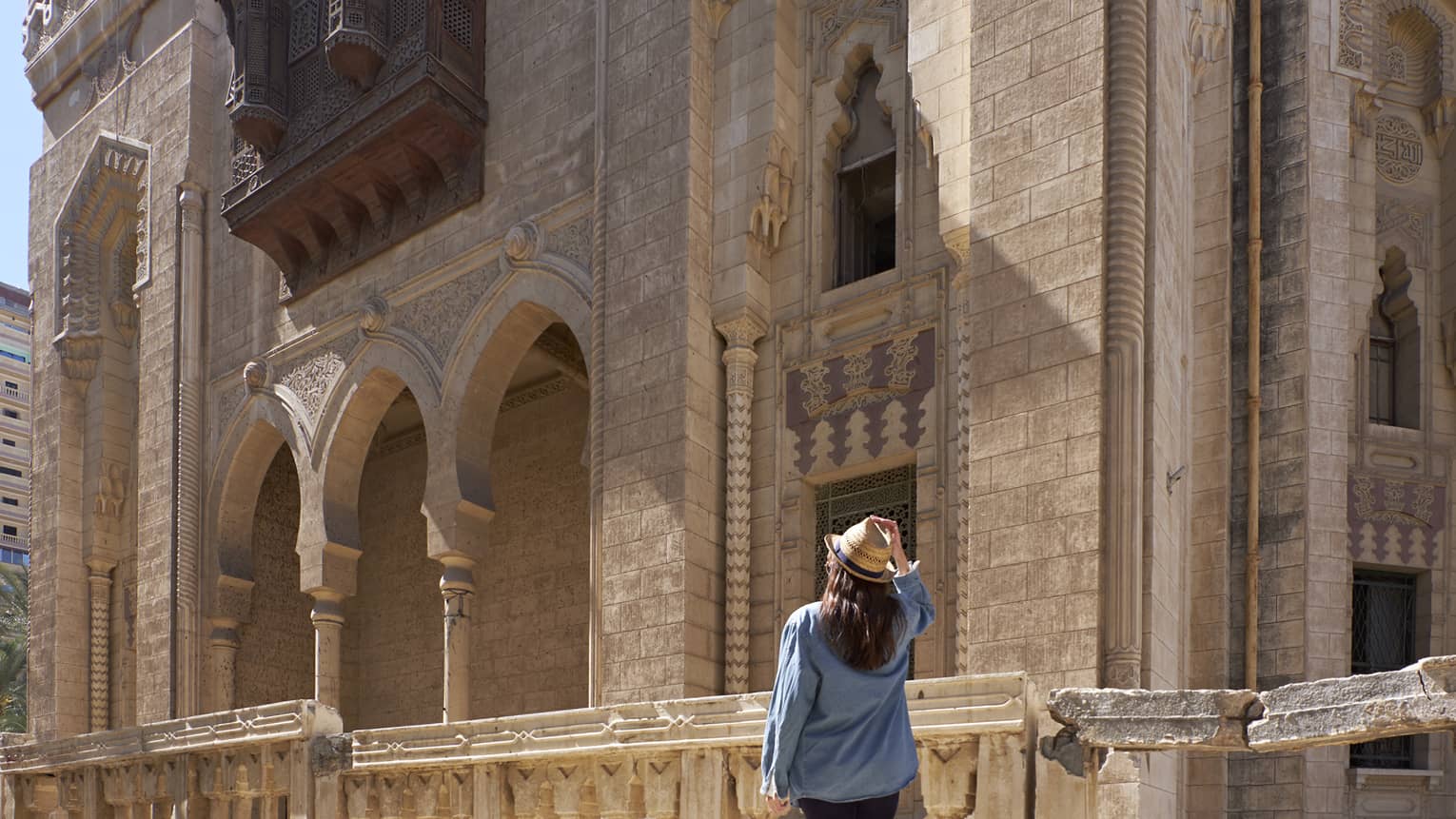 Woman looks up at historic palace exterior in Alexandria, Egypt 