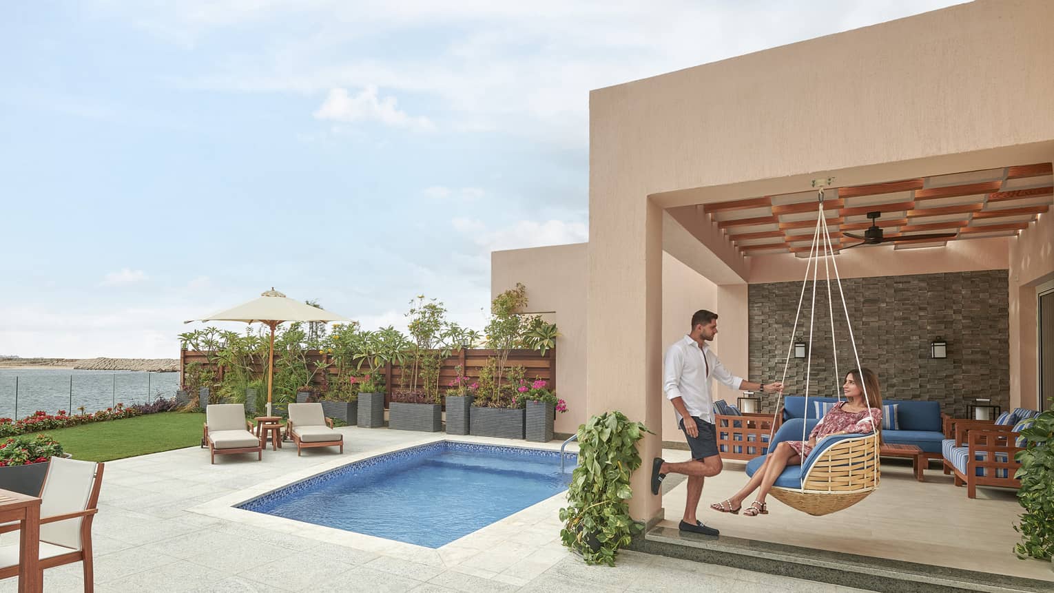 Woman sits in a hanging lounge chair on pool terrace