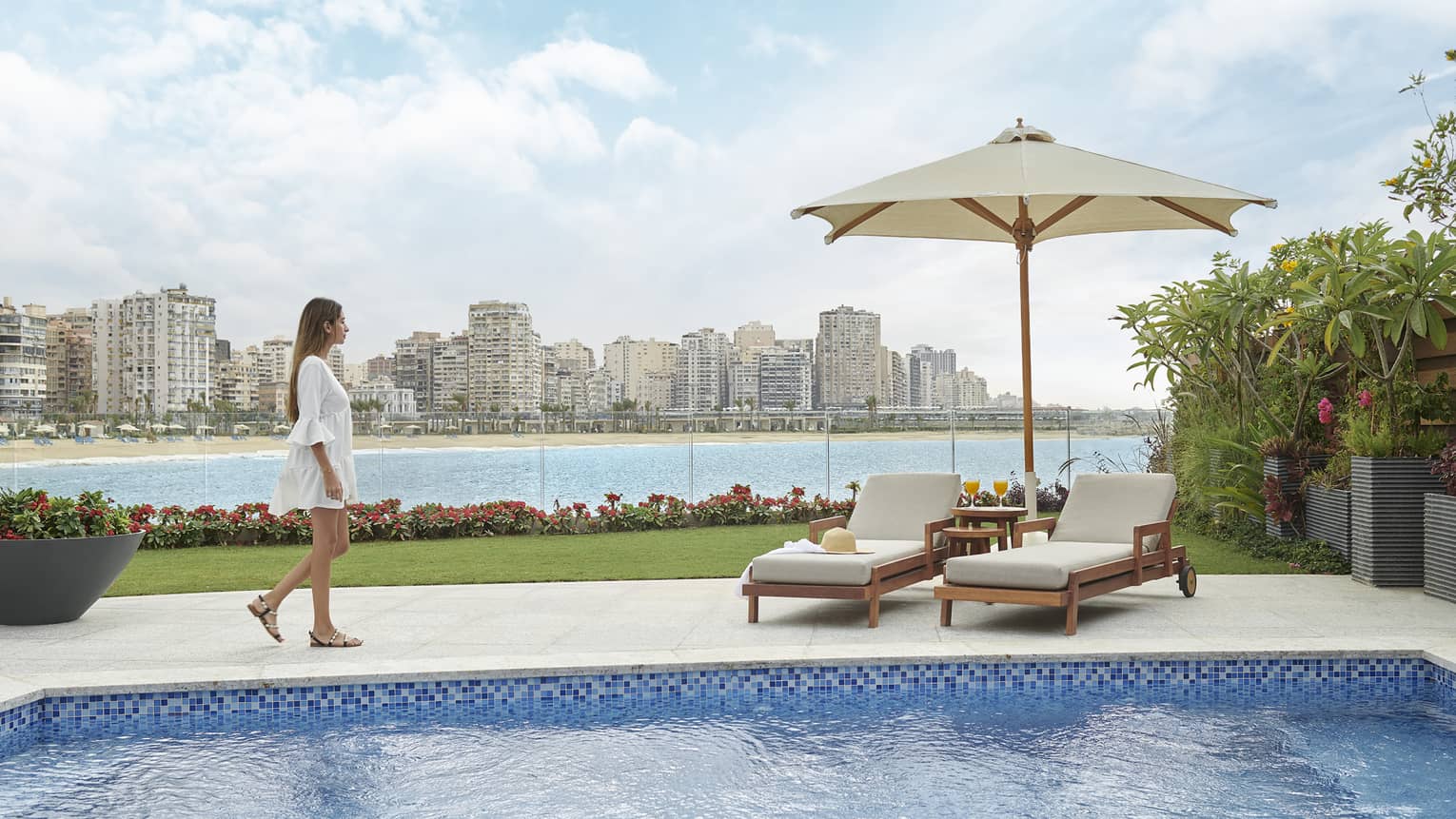 A women walking to a poolside cabana overlooking the city skyline