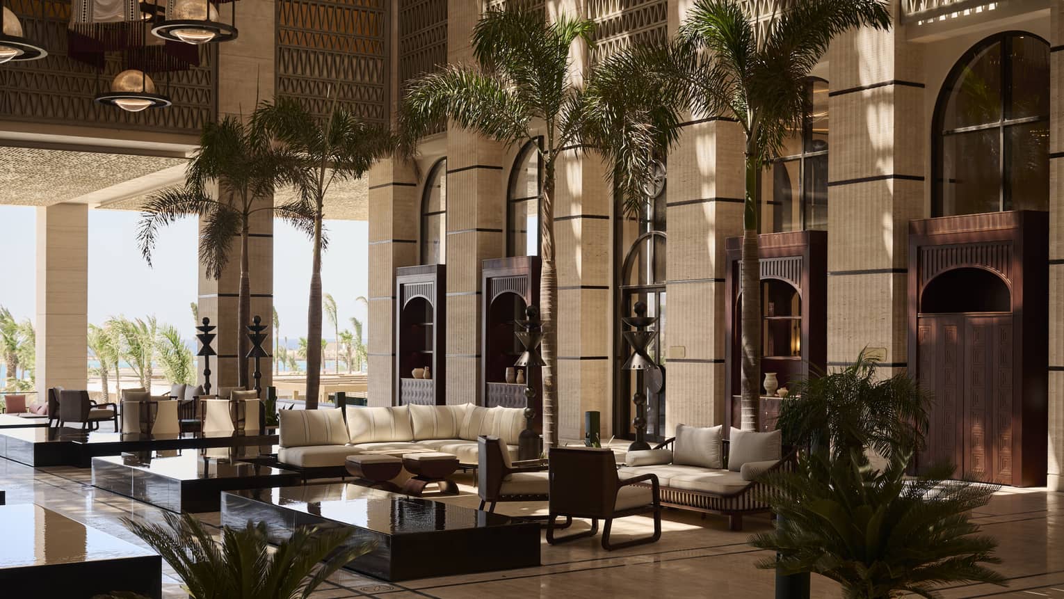 Interior lobby of a luxury resort featuring extra tall ceilings and opening to sea-view terrace