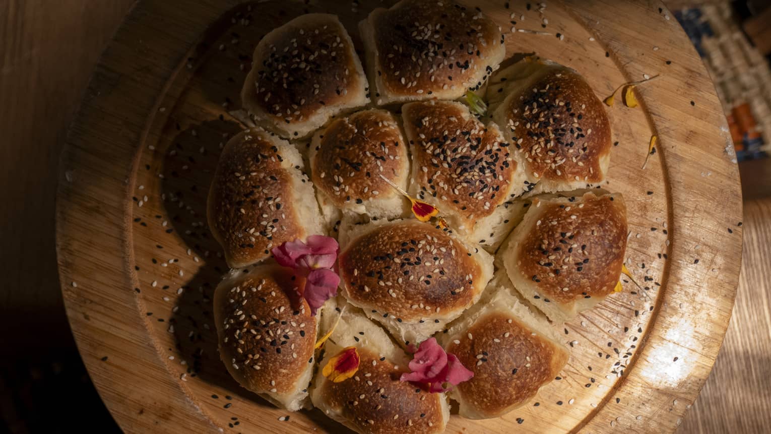 Browned baked bread arranged in a circle on round wooden tray