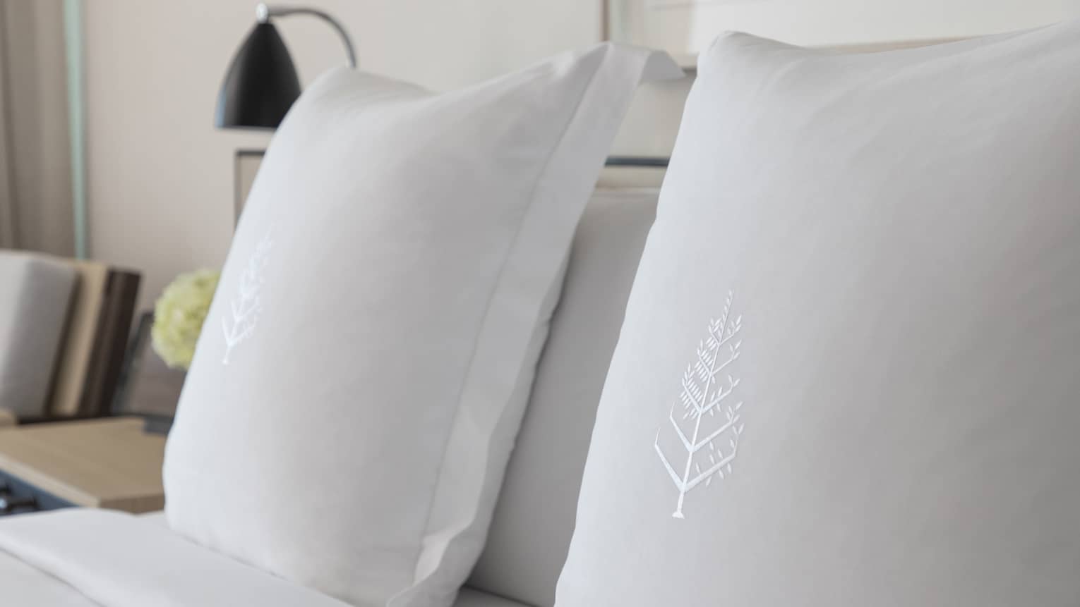 Two white sham pillows on bed with embroidered Four Seasons logos