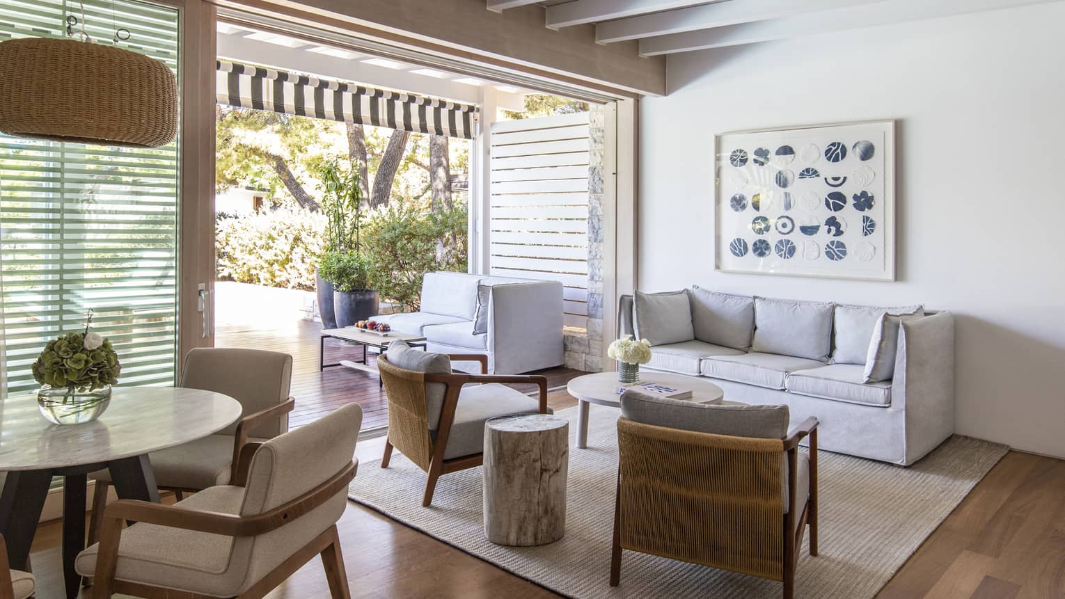 Living room with grey sofa, two chairs, dining table, walk-out terrace