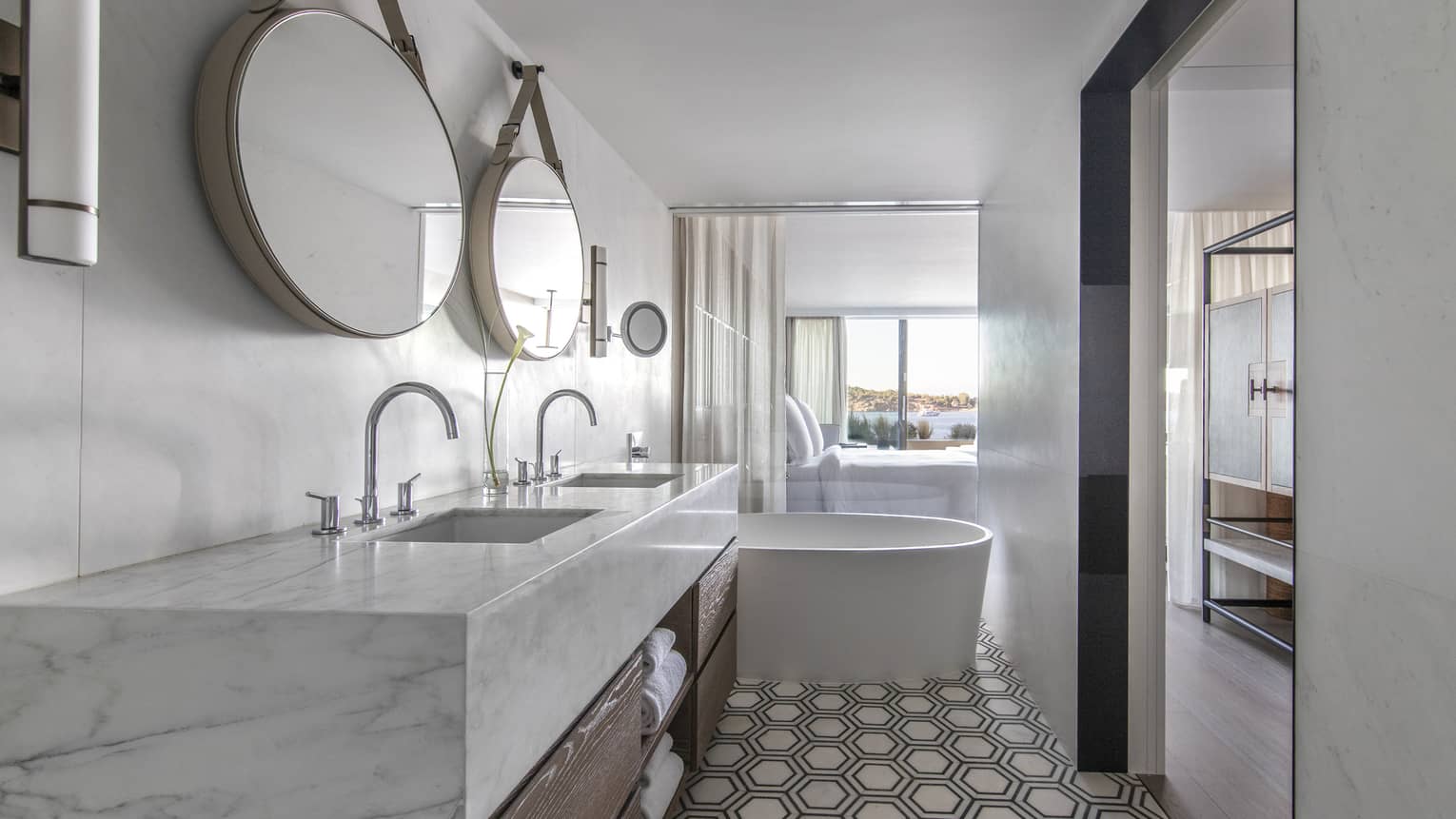 Bathroom with marble-topped double vanity, two round mirrors, tub