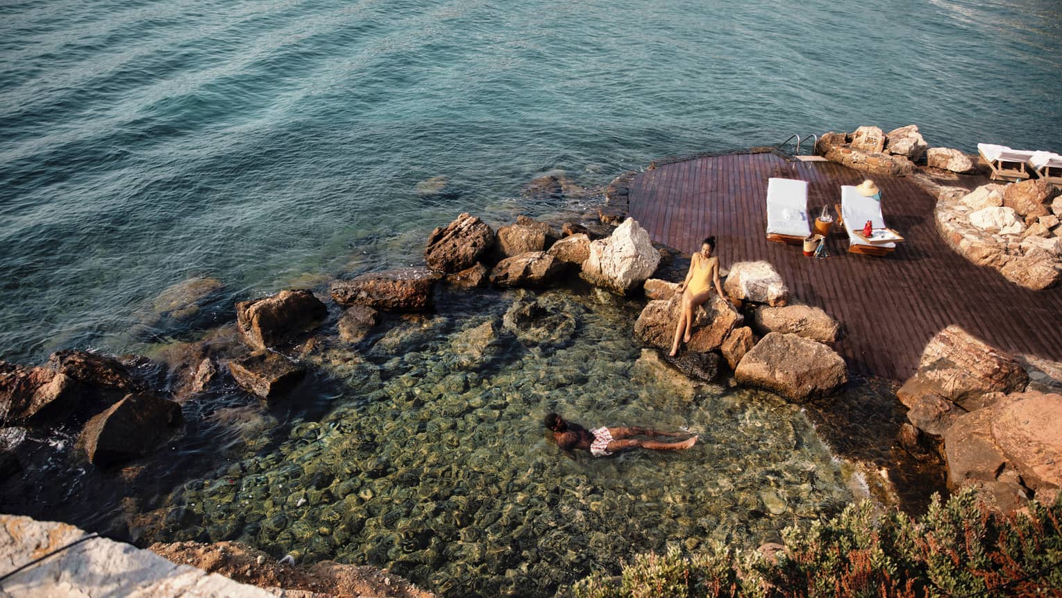 Couple lounging in clearwater cove beside platform with two white lounge chairs
