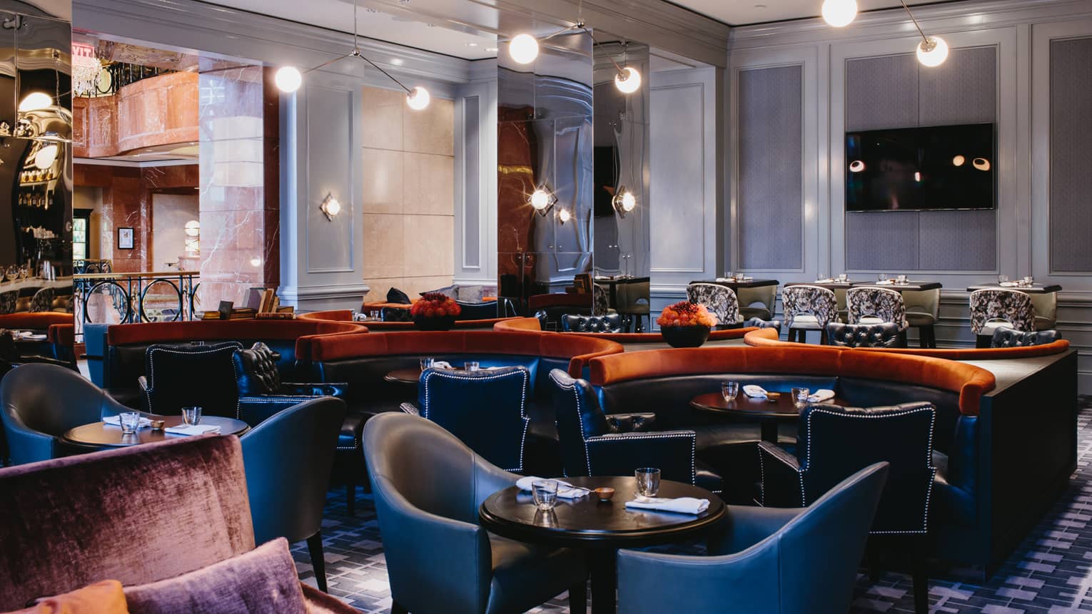 Leather chairs, curved booths around cocktail tables in Bar Margot