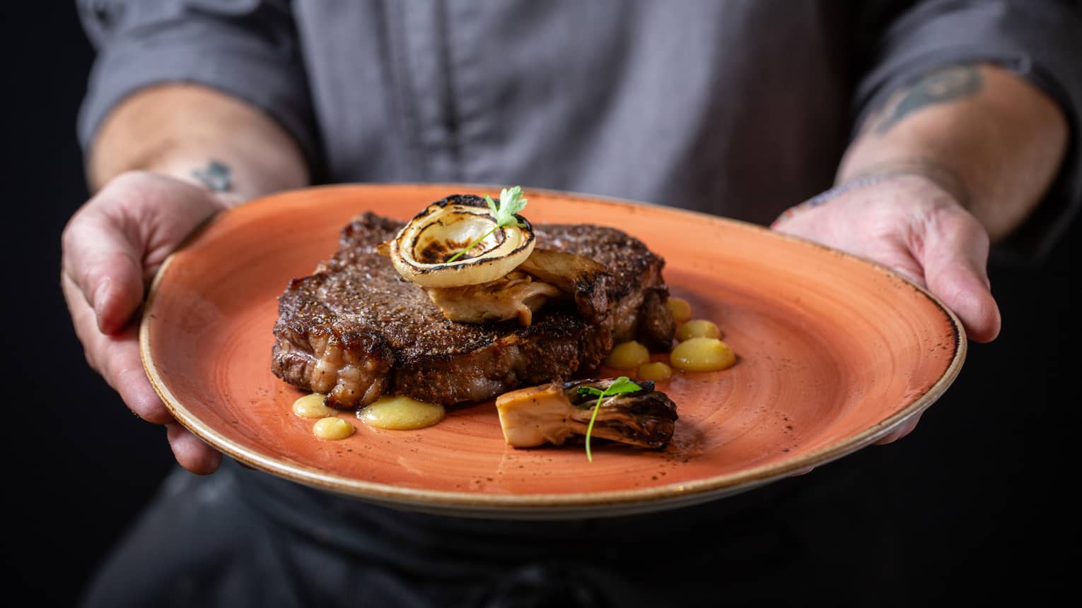 Ribeye on an orange plate with yellow sauce