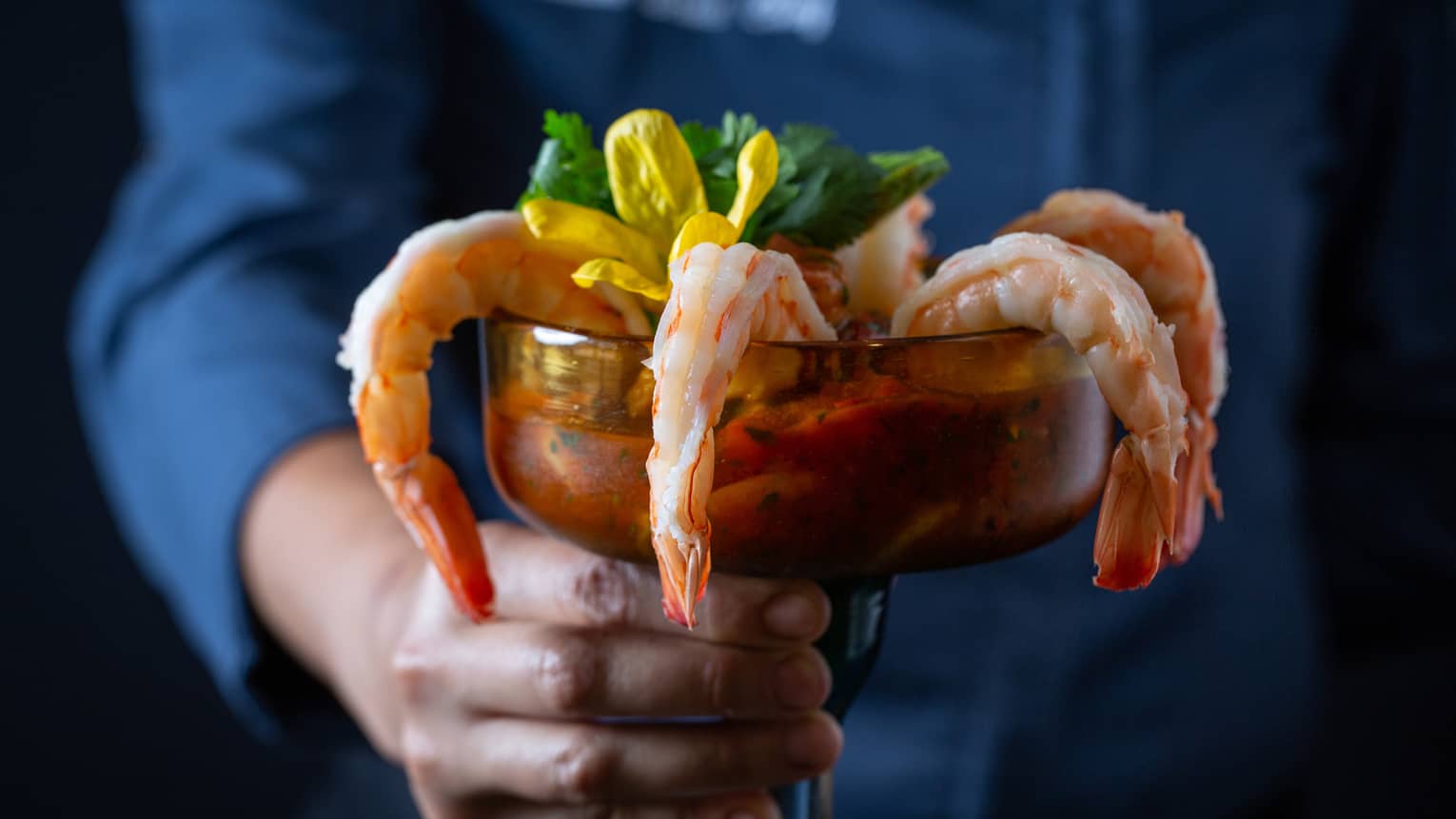 A hand holding cocktail shrimp designed to look like a cocktail drink.