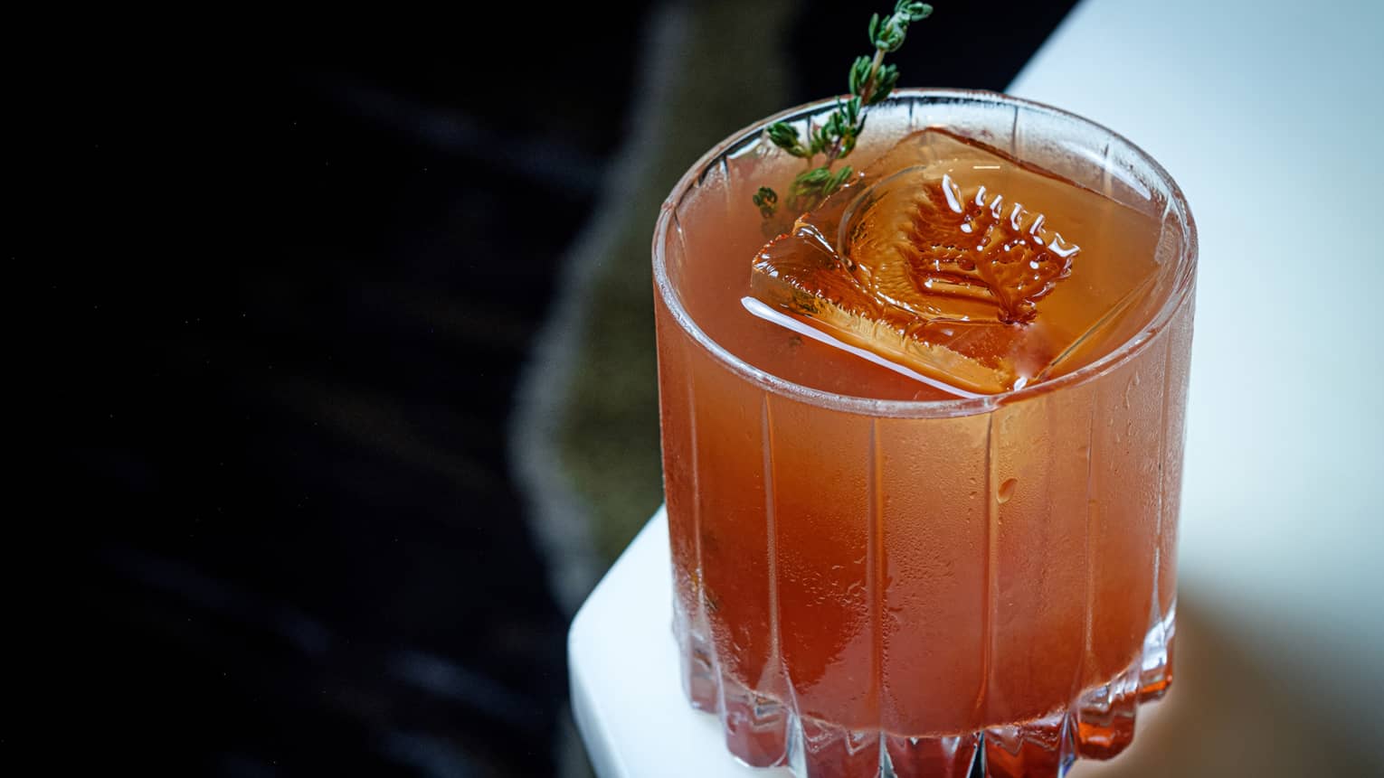 An amber coloured cocktail with a leaf imprinted into the ice.