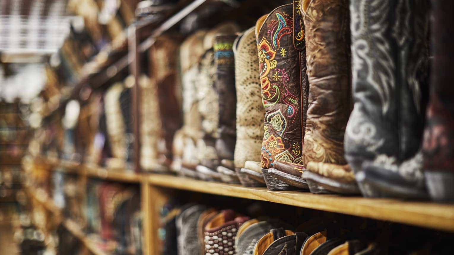 Shelves of cowboy boots of varying colours including black, brown and beige.
