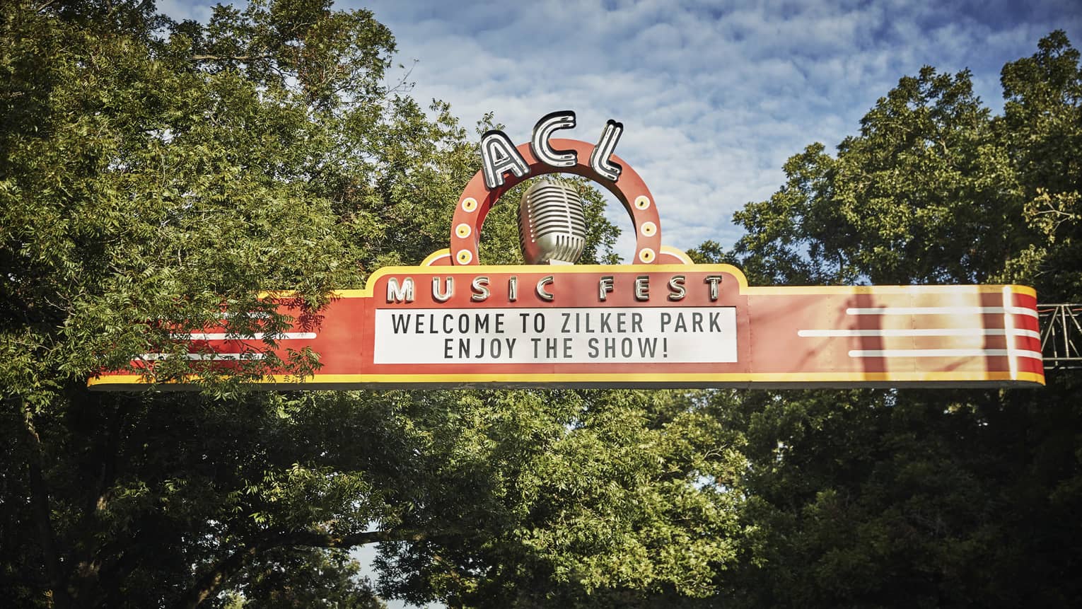 A large orange sign in the trees that says ACL Music Fest.