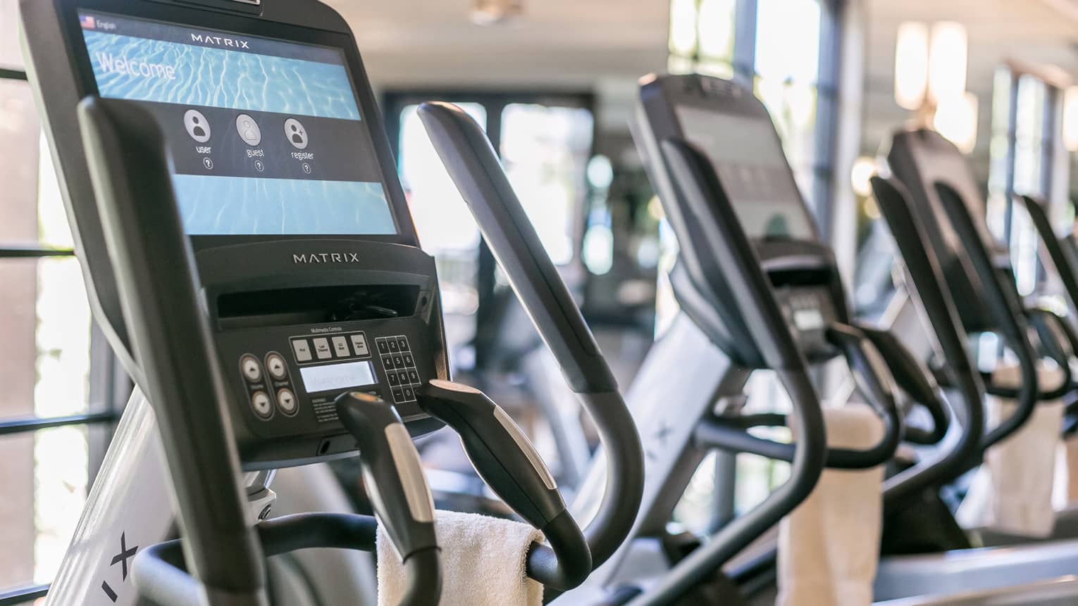 Close-up of Matrix cardio machine screens and handles in a row