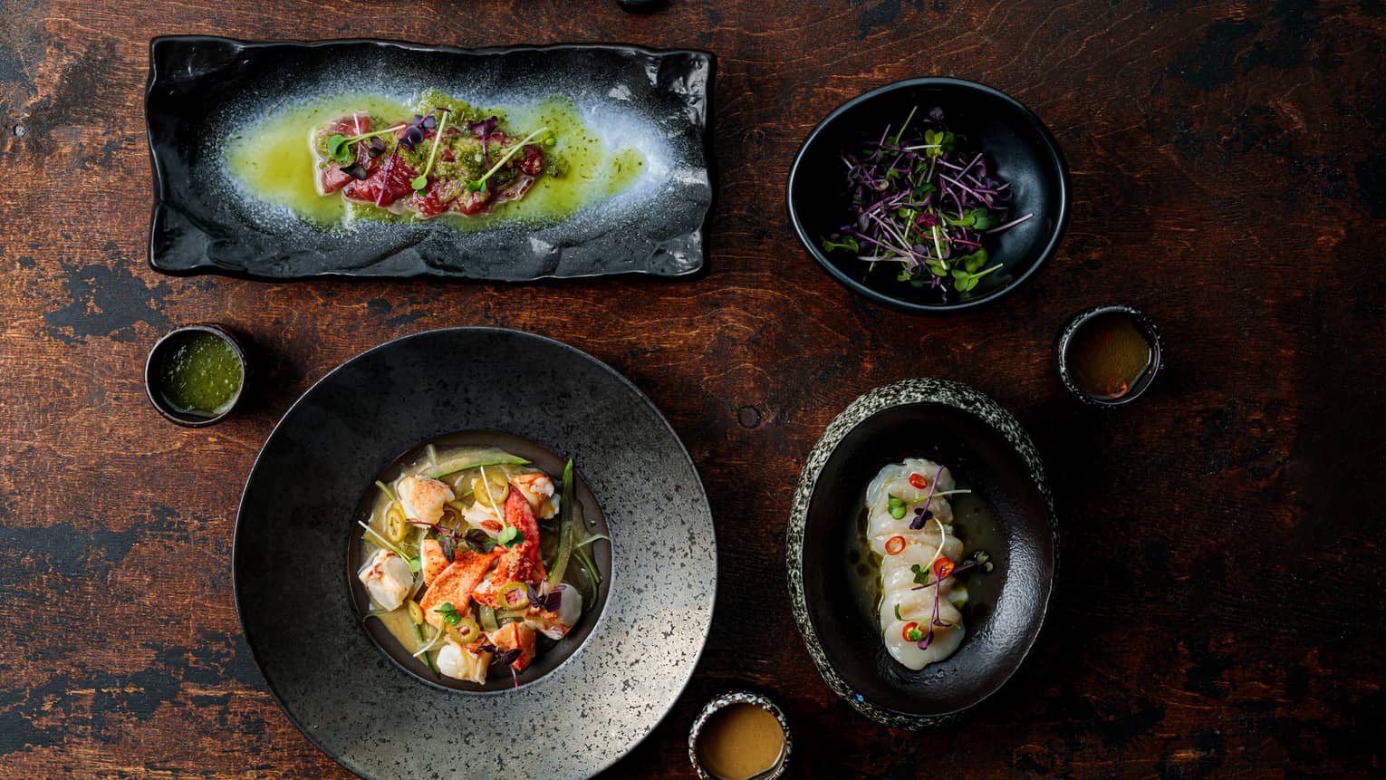 Several black plates filled with various asian cuisine.