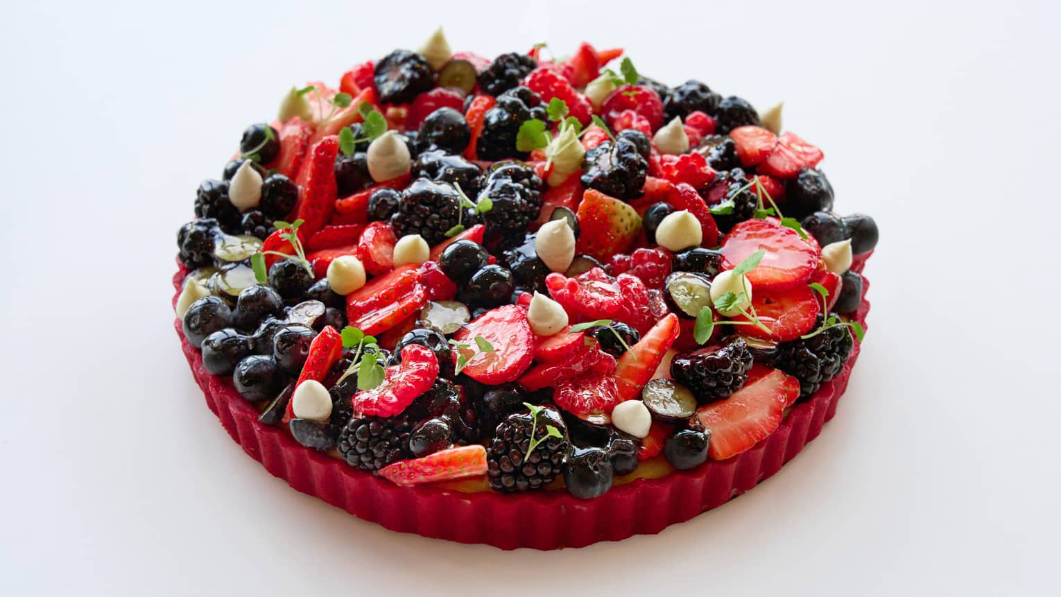 Fruit tart topped with assortment of fresh berries and dollops of cream