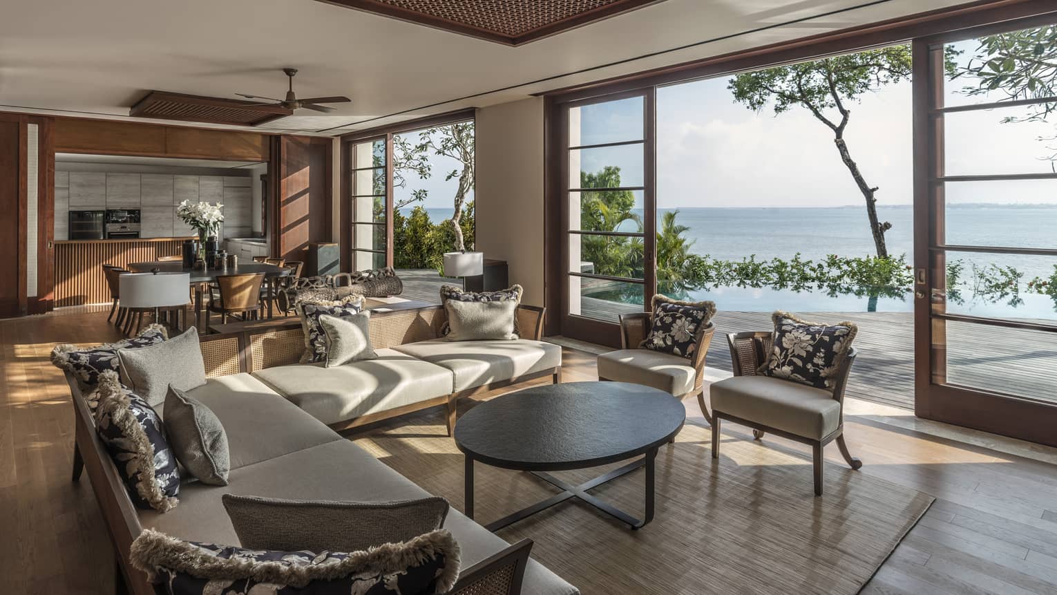 Large Imperial Villa living room with L-shaped white sofa, black-and-silver pillows, dining tables, open walls to sunny patio