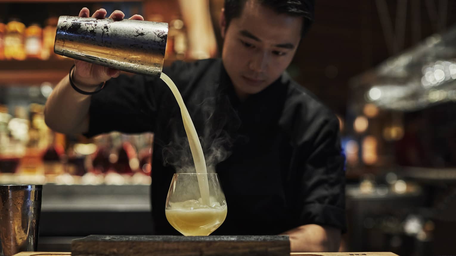 Bartender pours mixed cocktail into tumbler