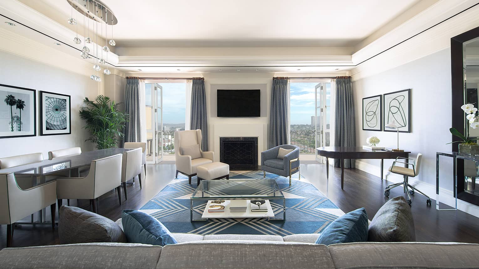 Ambassador Suite back of long sofa, dining table, armchairs by fireplace, TV, open balcony doors