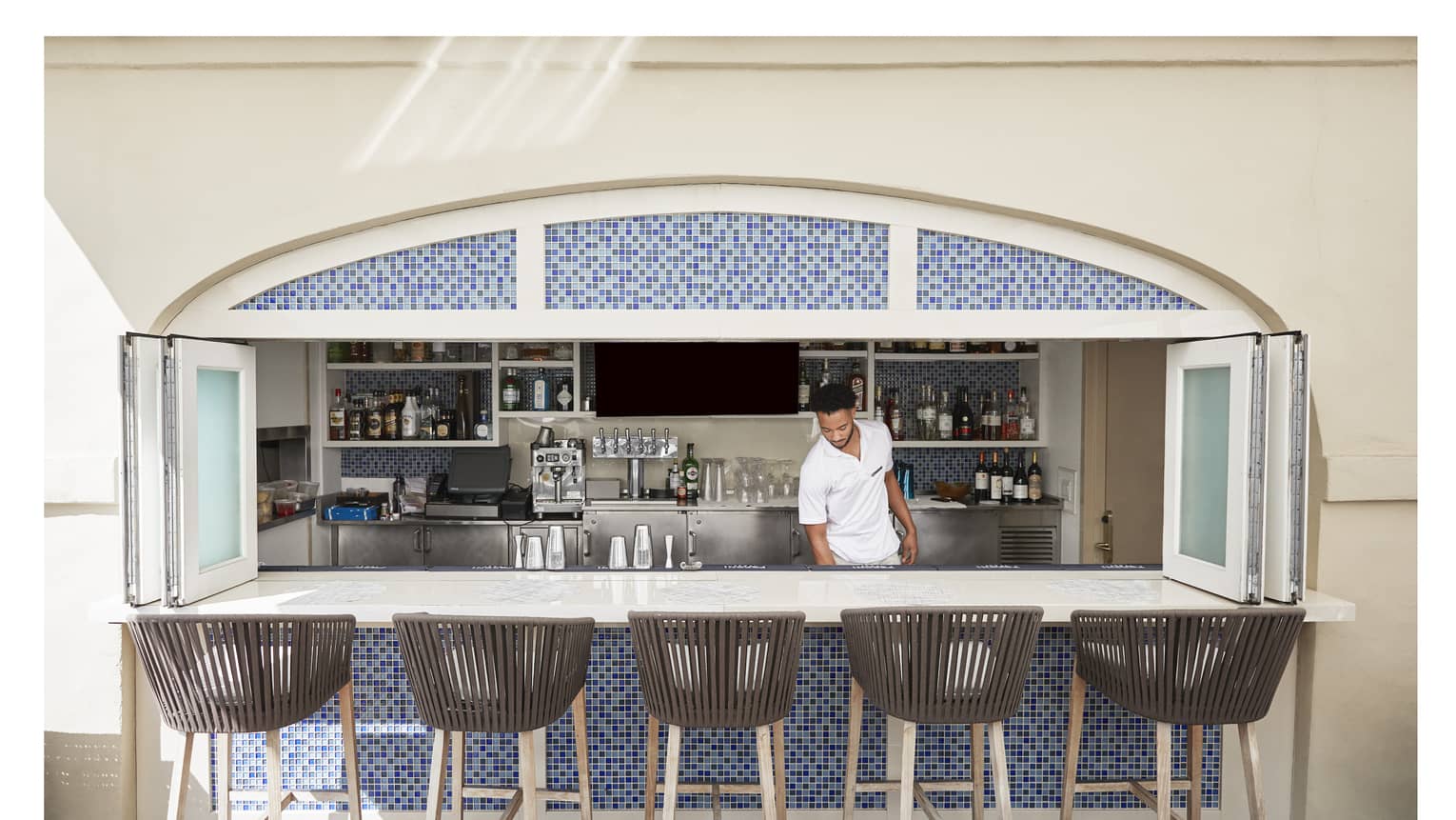 A team member standing behind a bar with stool.