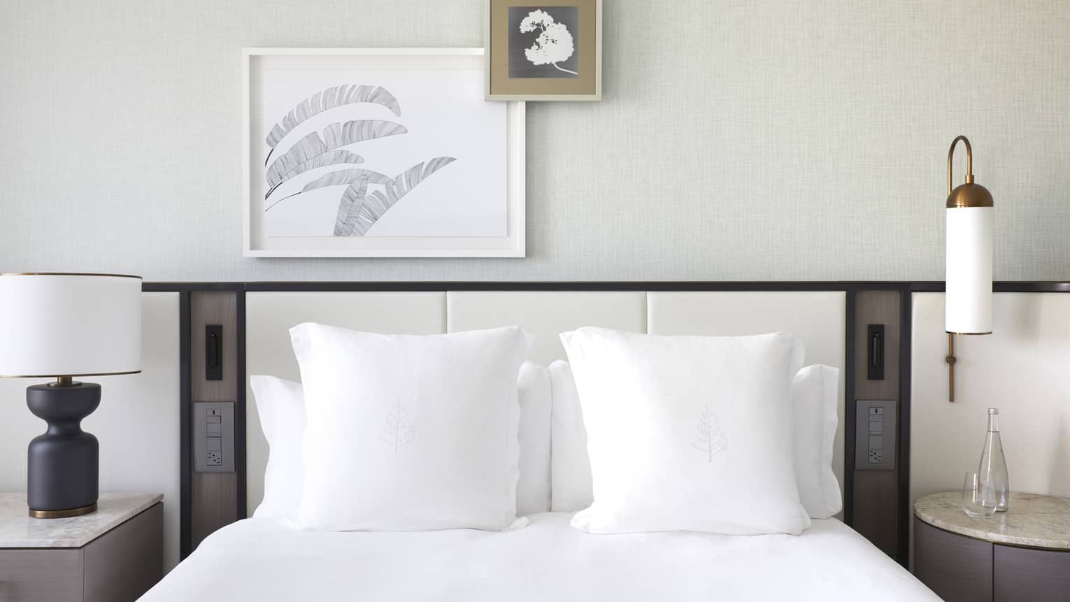 Bed with white sheets and pillows, asymmetrical artwork overhead