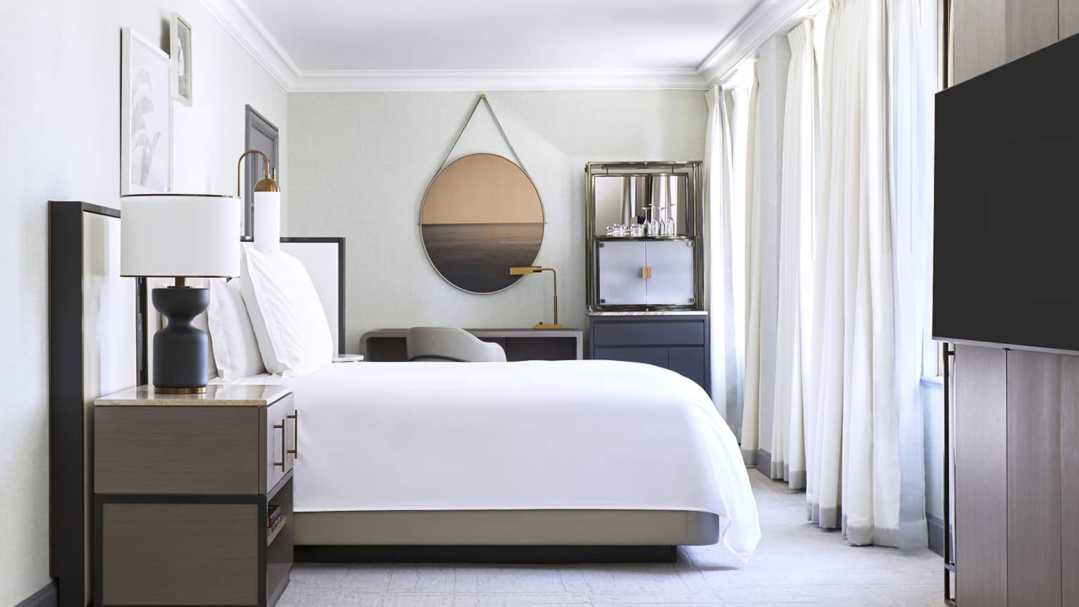 Bedroom with circular mirror and wall-mounted TV