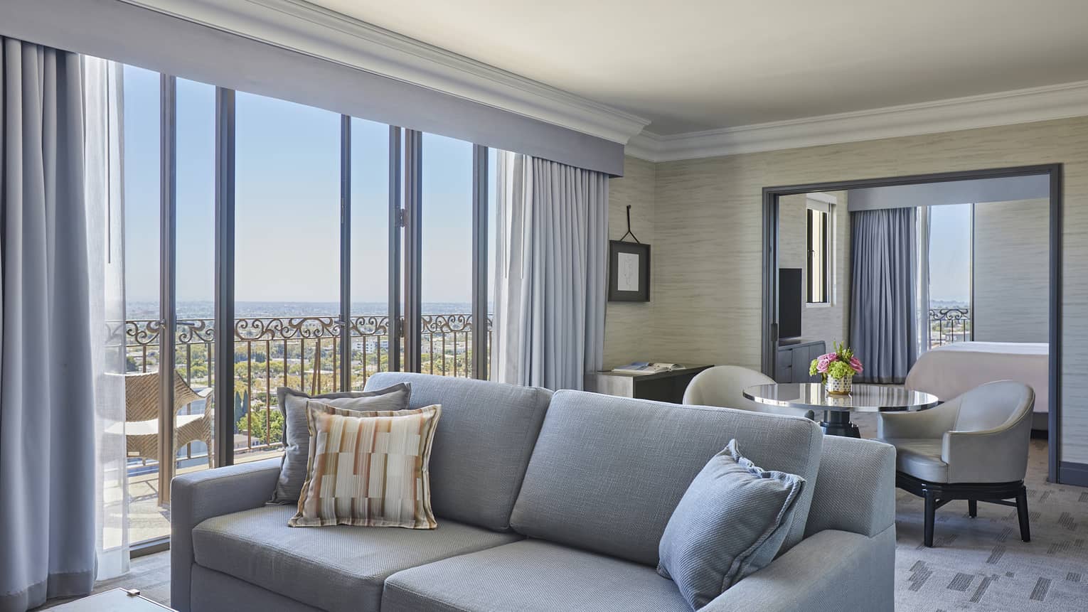 Grey sofa with small table and two chairs behind it, walk-out balcony