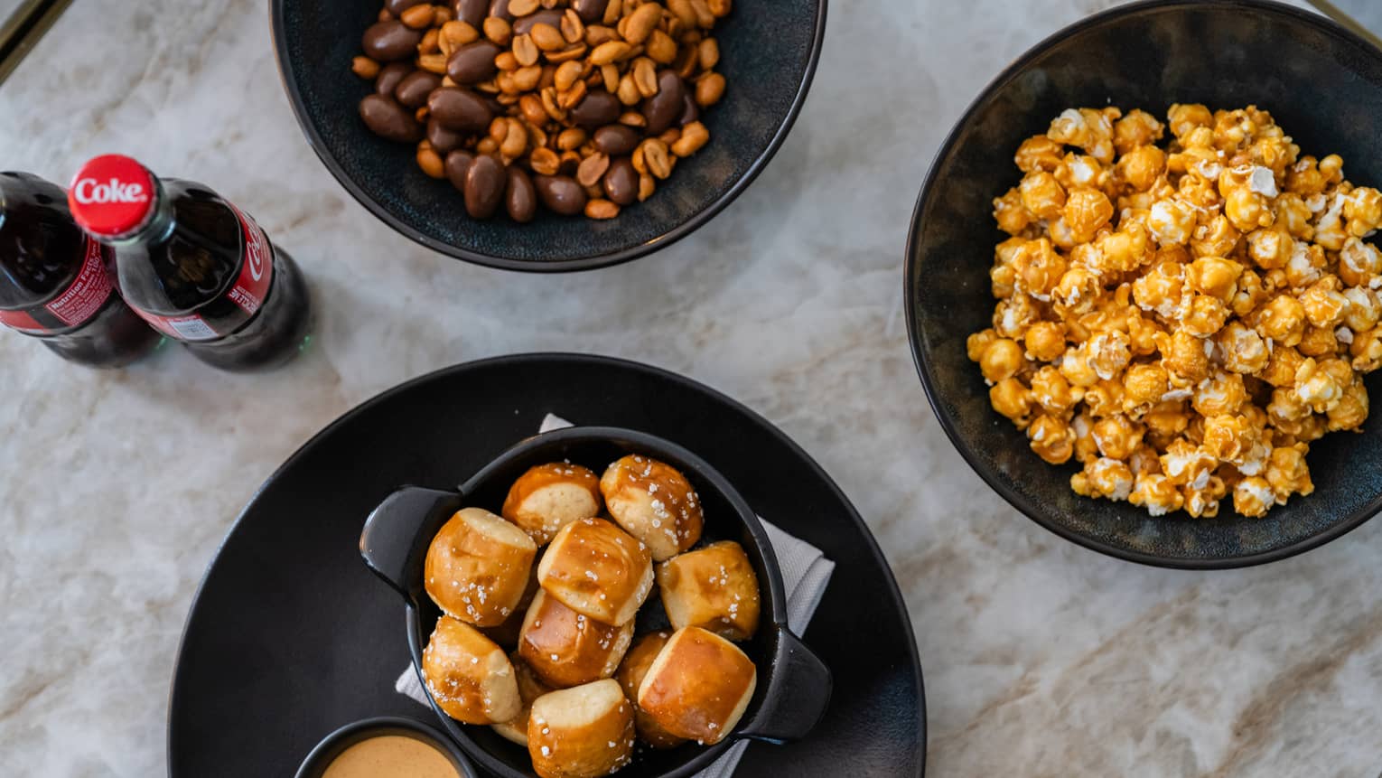 Pretzel bites, a bowl of popcorn and snacks with a soda