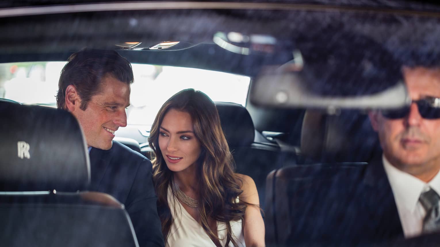 Man and woman in the back seat of a Rolls Royce house car