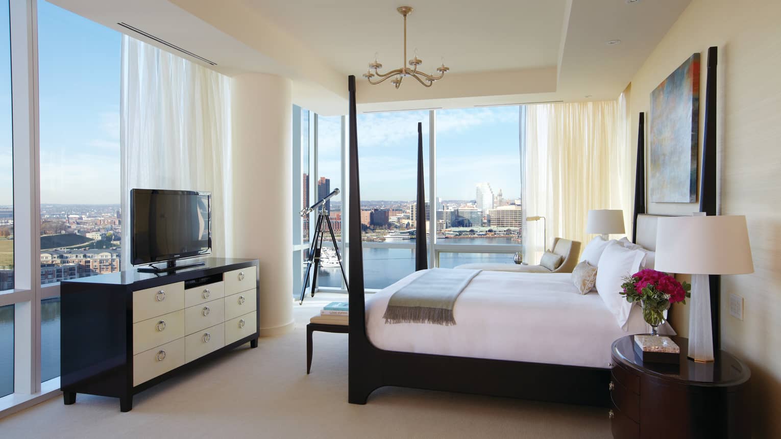 Presidential Suite black poster bed in front of dresser, TV, floor-to-ceiling corner windows