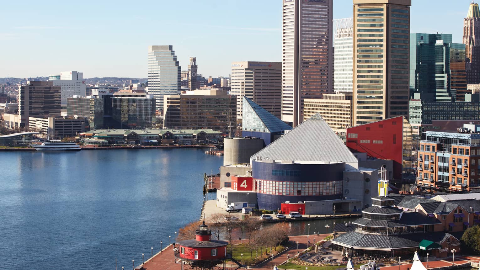 Looking down at Baltimore buildings, boardwalk along waterfront on sunny day