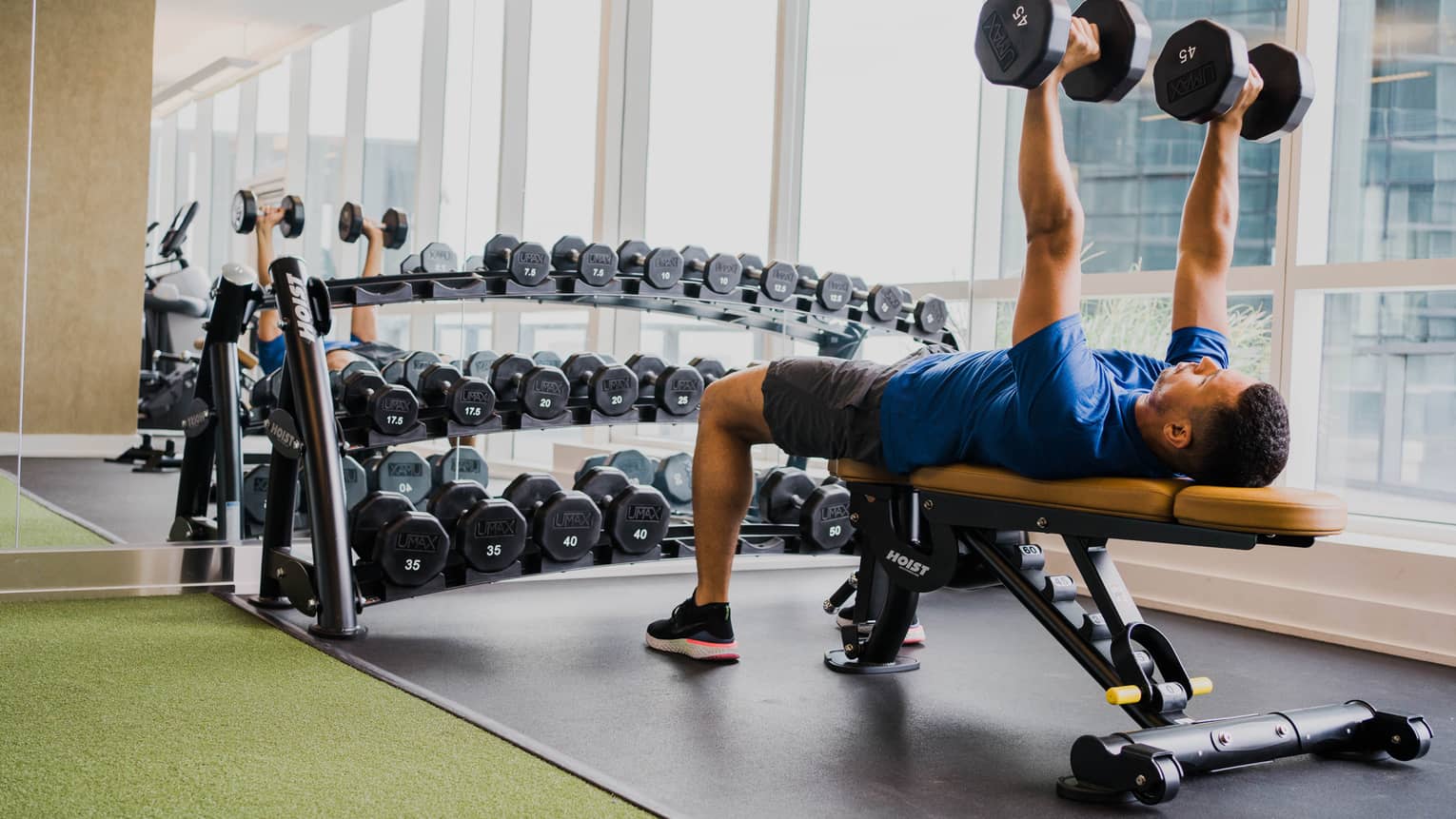 A man lifting two weight while laying on a bench.