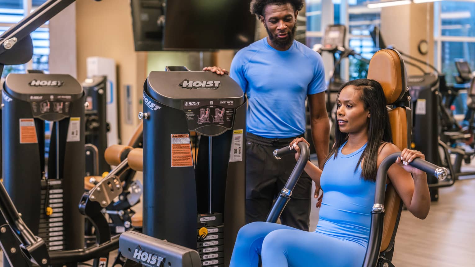 Two guests in a gym, one guest using a gym machine.