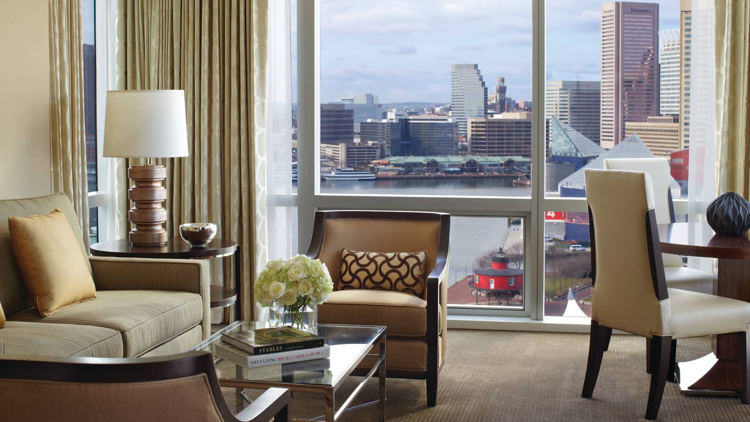 Lighthouse Suite chairs, sofa, coffee table with two books by windows with harbour views