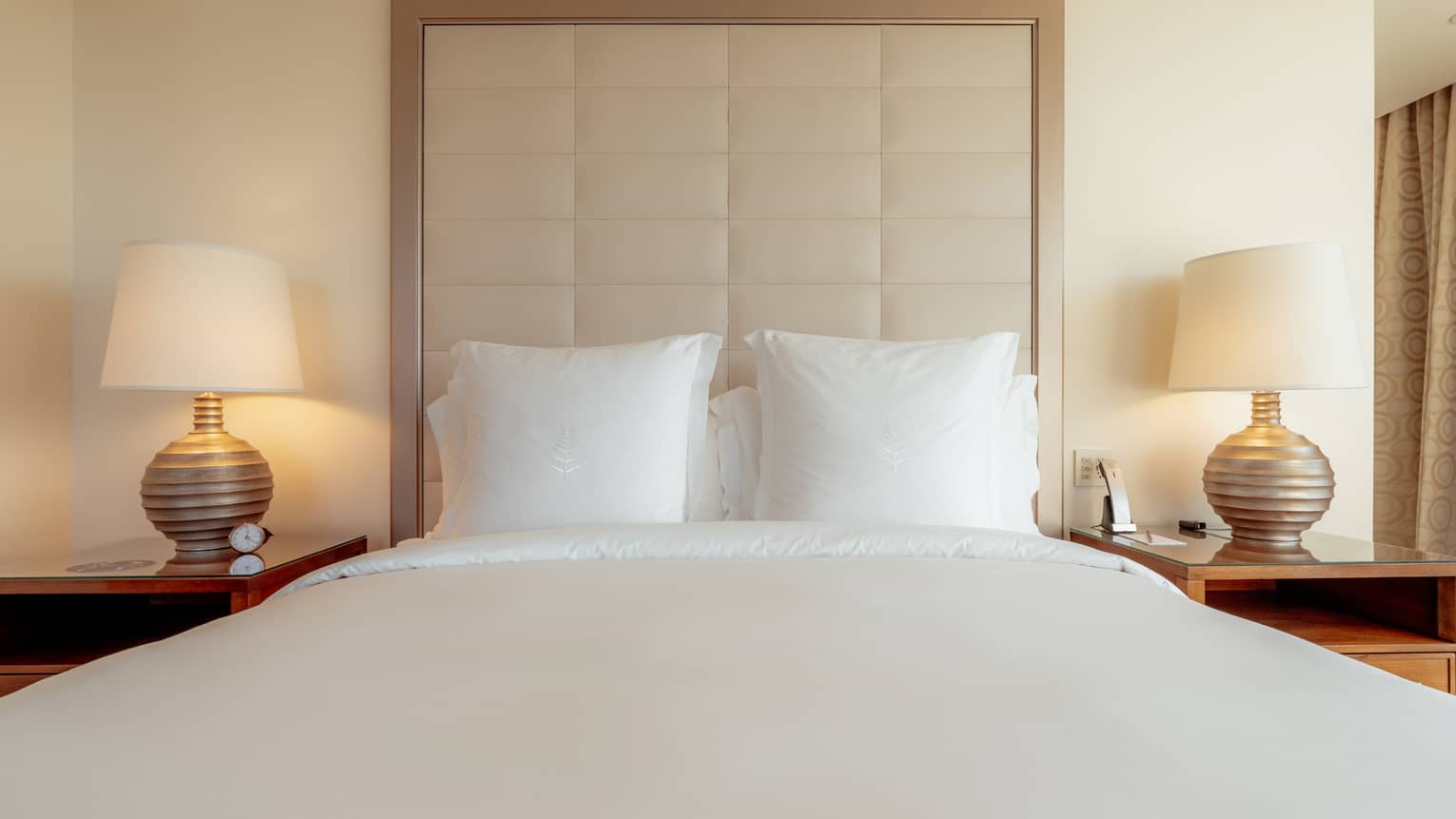 King bed with white sheets and high headboard in luxury hotel room