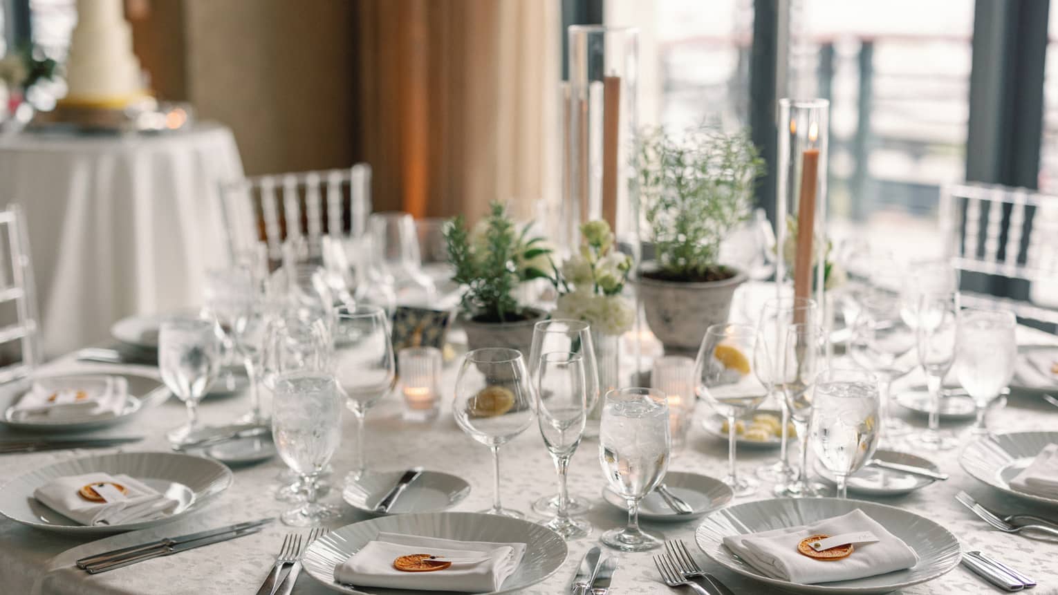 A dining table set with plates, utensils, napkins, wine glasses and candles