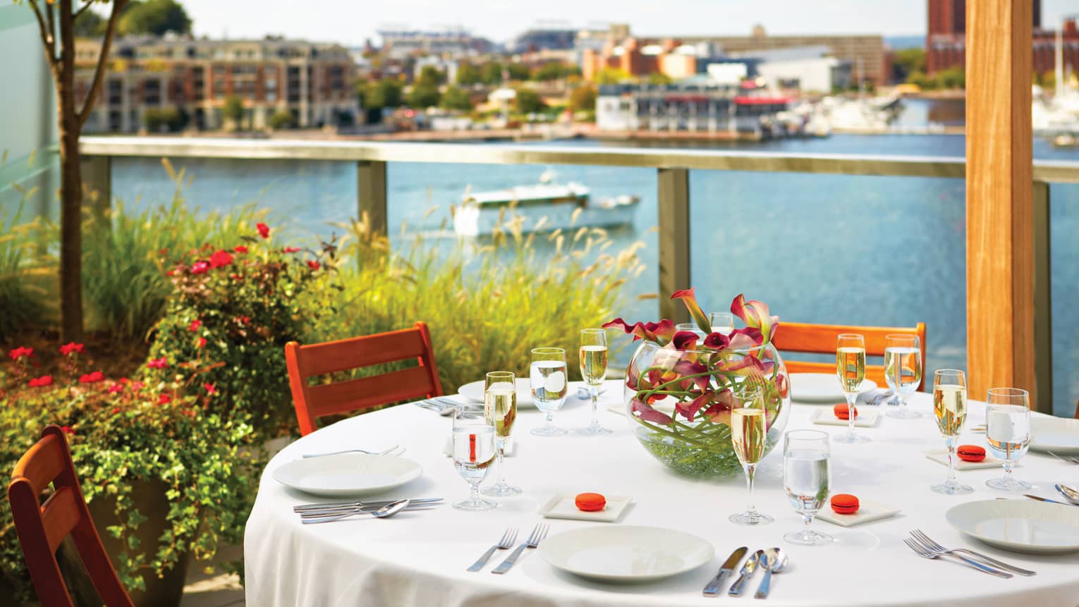 Round outdoor dining table with Champagne glasses on patio overlooking river