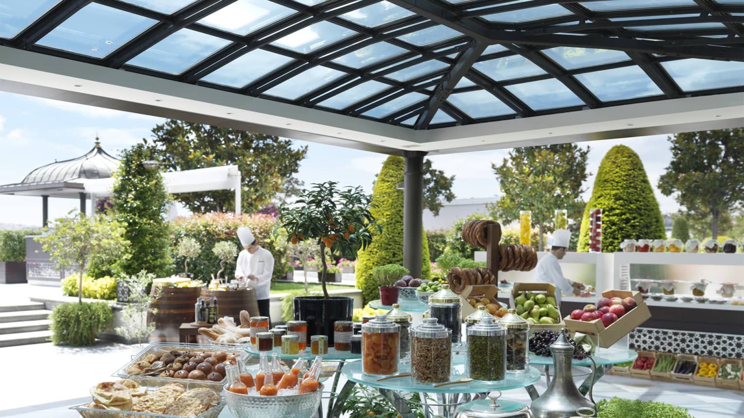 Brunch buffet on glass display on outdoor patio, chefs in white uniforms