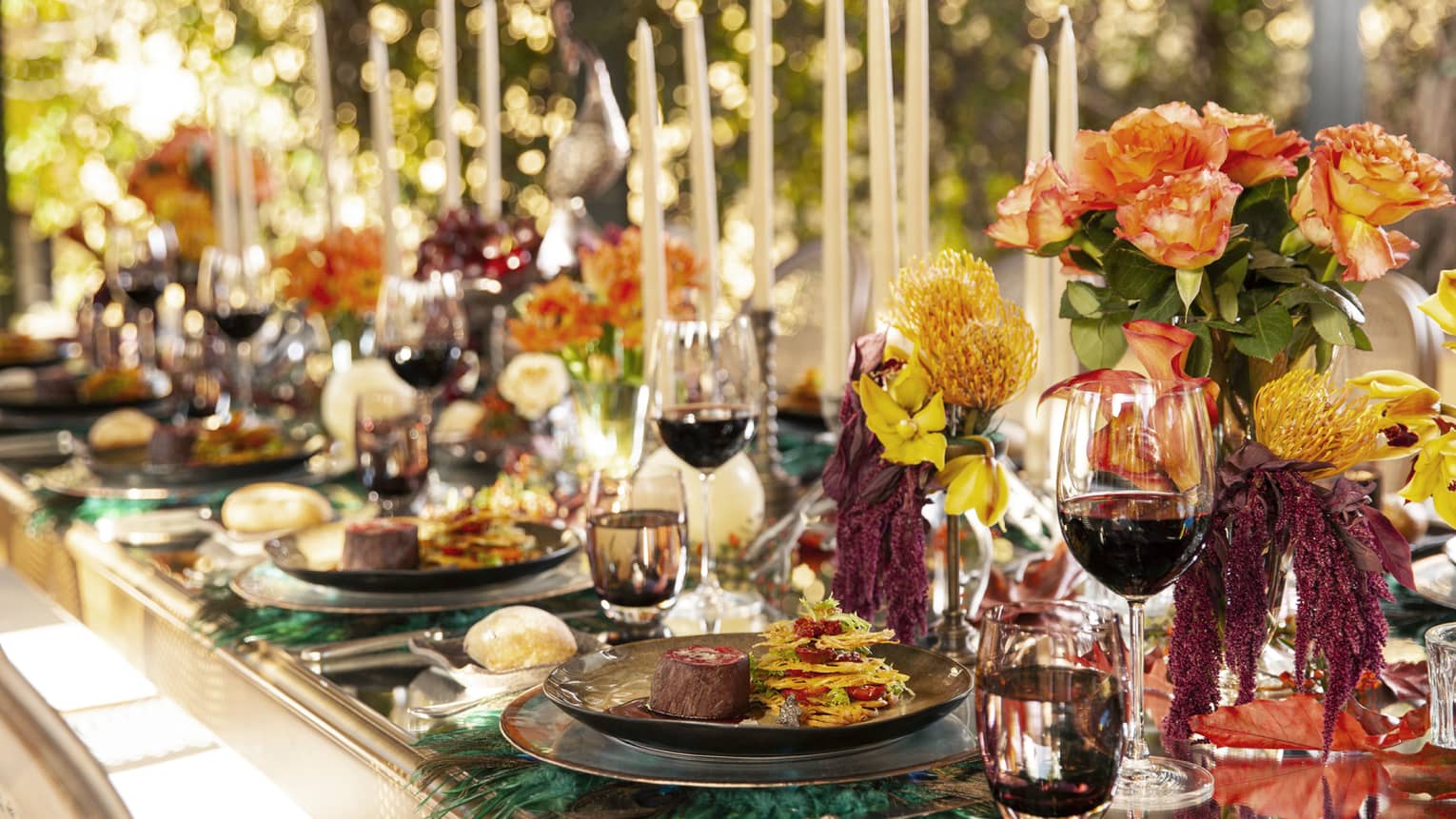 Elegant wedding dining table with red wine in glasses, flowers and tall candles