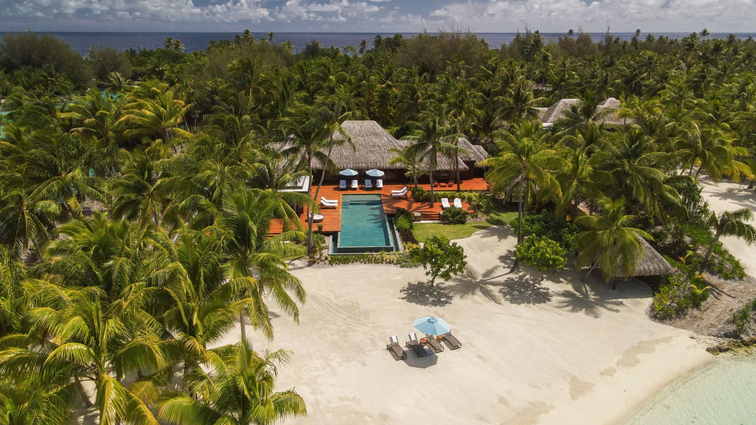 Aerial view of Bora Bora villa with pool on edge of beach, surrounded by palm trees