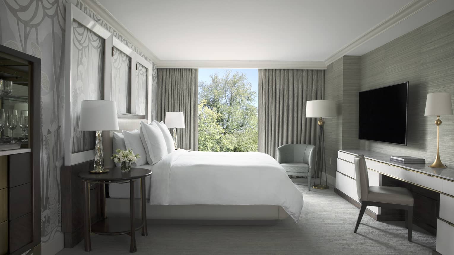 Garden Suite hotel room bed with white linens across from desk, tv