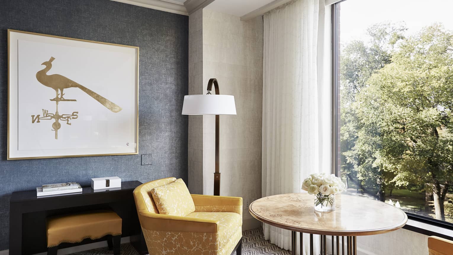 Two yellow upholstered arm chairs face outward toward window overlooking trees
