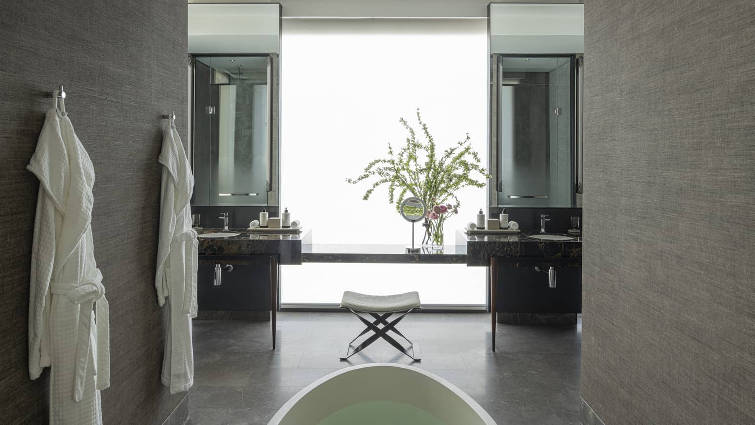 Luxury bathroom with standalone tub and two hanging bathrobes
