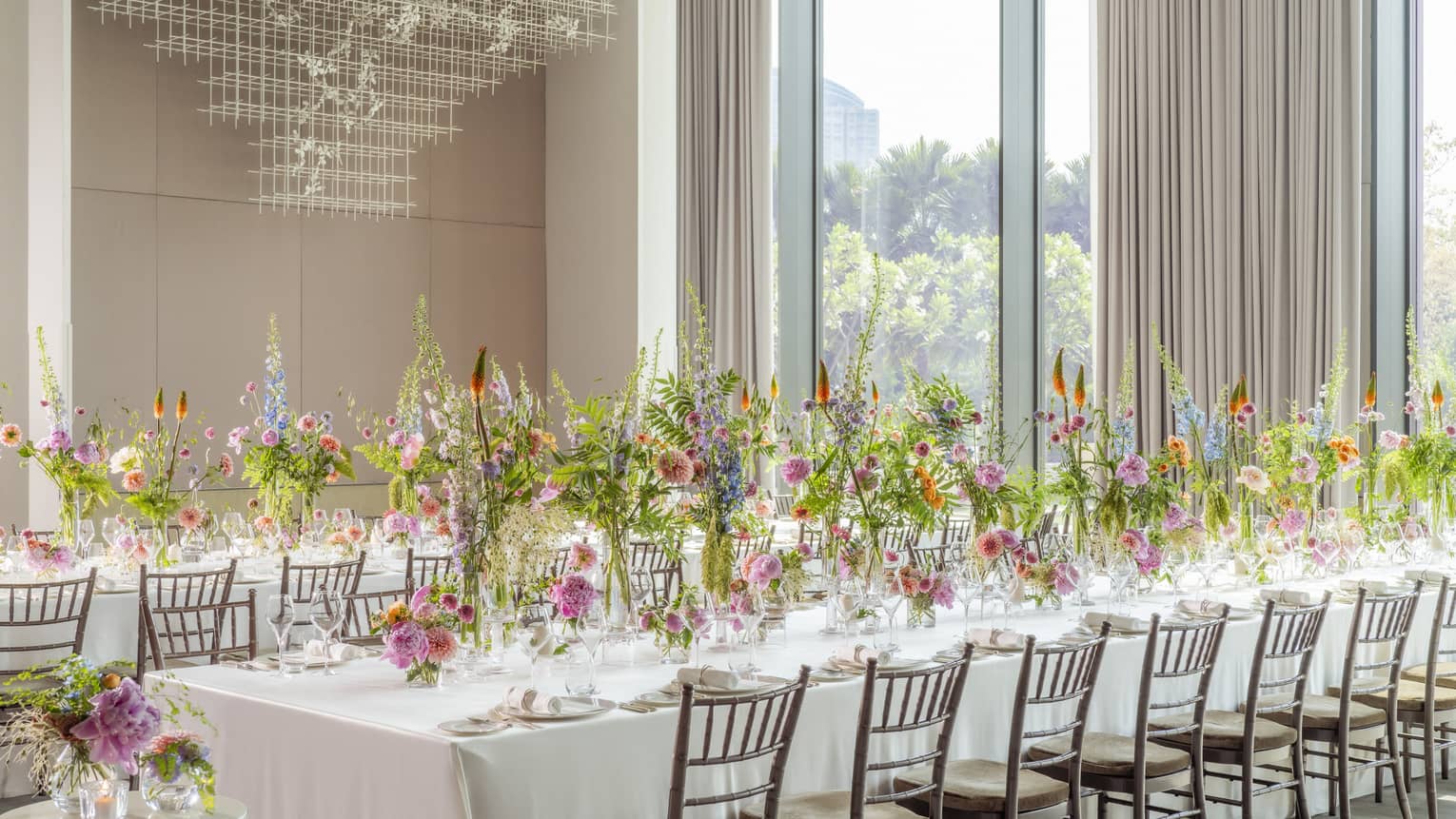 Ballroom set classroom-style with white linen?covered tables and tall floral centrepieces