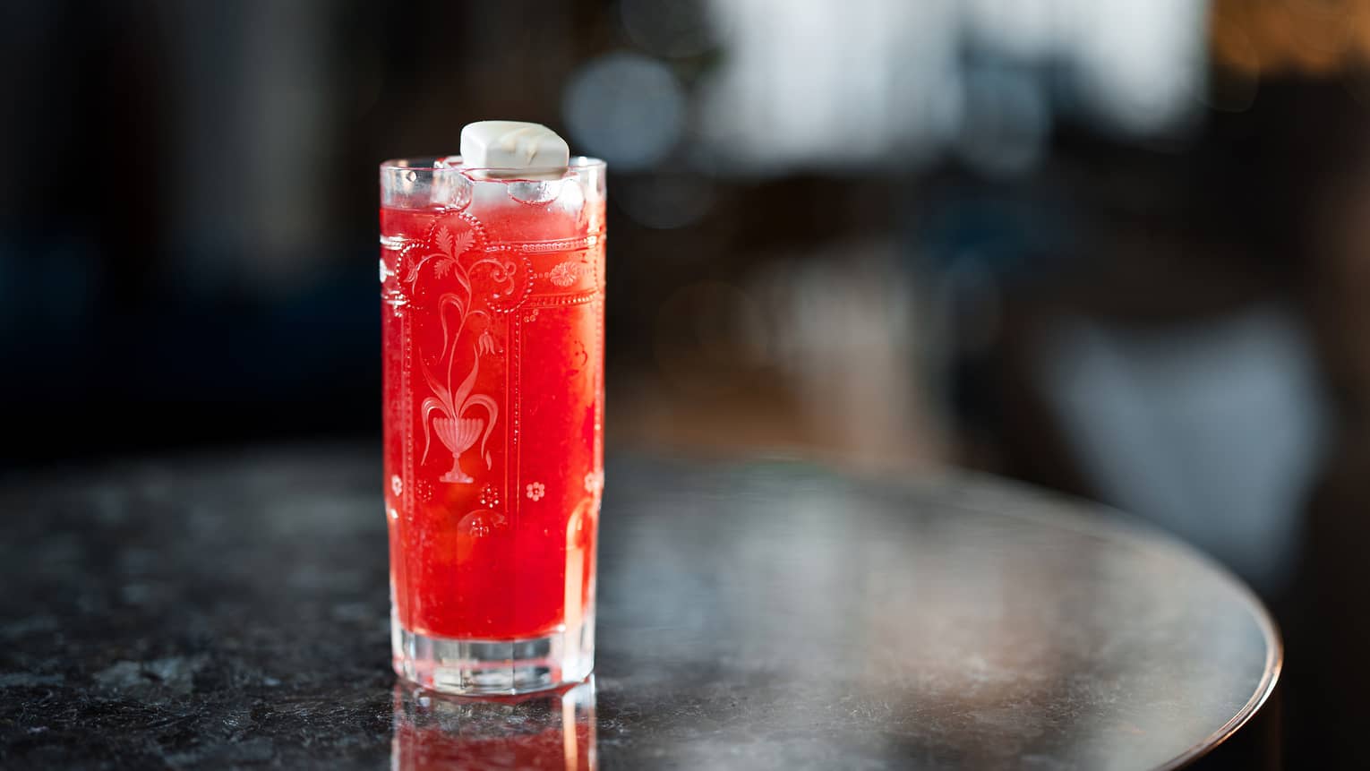 Bright-red cocktail in etched highball glass on black marble table