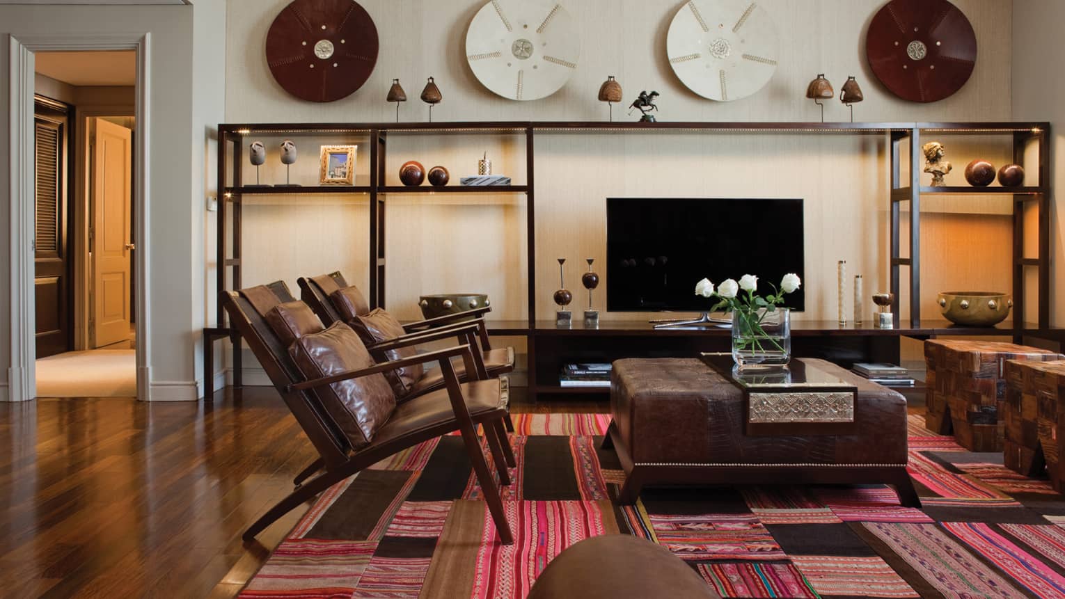 Modern brown leather armchairs and large ottoman with fresh flowers, modern and wood Argentine-inspired art