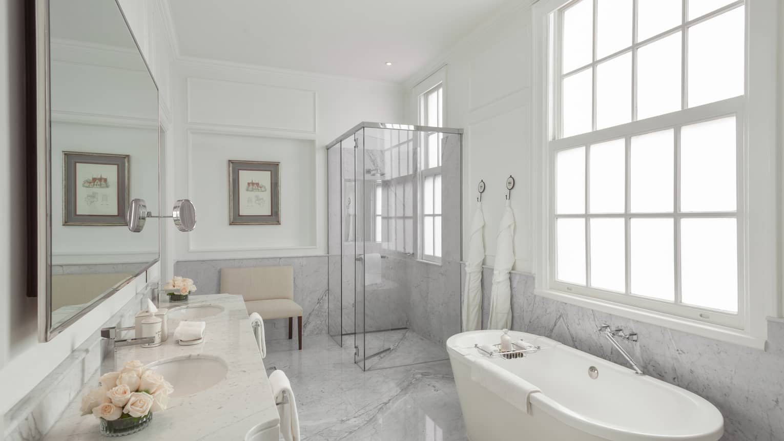 The La Mansion Bathroom is filled with a porcelain bath tub, glass shower and long mirror